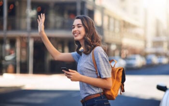 Cropped shot of an attractive young woman sending a text message while hailing a taxi out in the city