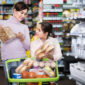 smiling woman with daughter choosing delicious bread in supermarket